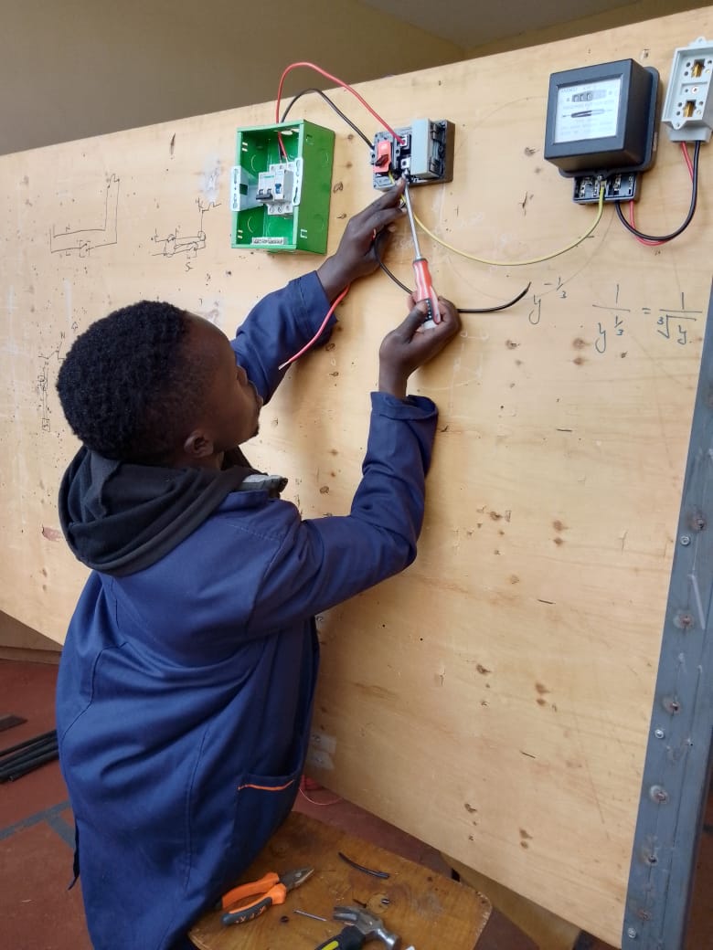 Students wiring an electrical control panel in a modern lab